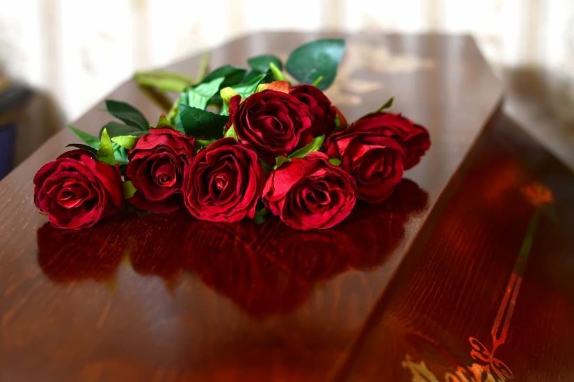 Rote Rosen liegen auf einem Sarg